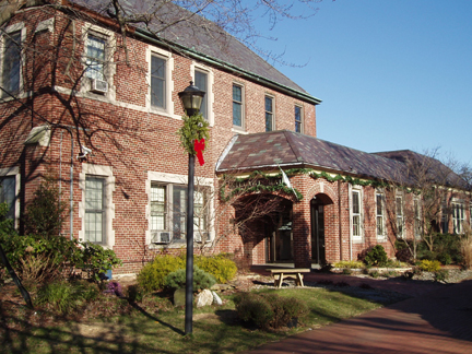 A substantial brick building featuring numerous windows and a sturdy facade, set against a bright sky.